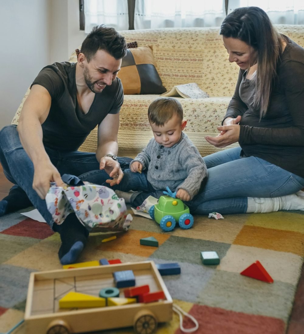 Parents with their little son opening a gift